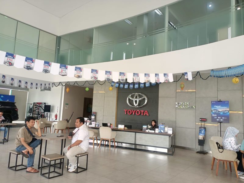 Suasana ruang pamer (showroom) Toyota di kawasan Jababeka, Cikarang, saat berlangsung Showroom Event Spektakuler Februari 2026. Sejumlah konsumen terlihat berkonsultasi dengan tenaga penjual terkait promo lini hybrid, termasuk New Veloz HEV dan Yaris Cross HEV yang ditawarkan dengan berbagai insentif menarik.